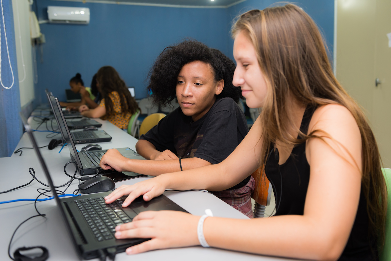 Jovens sentados em frente à computadores.