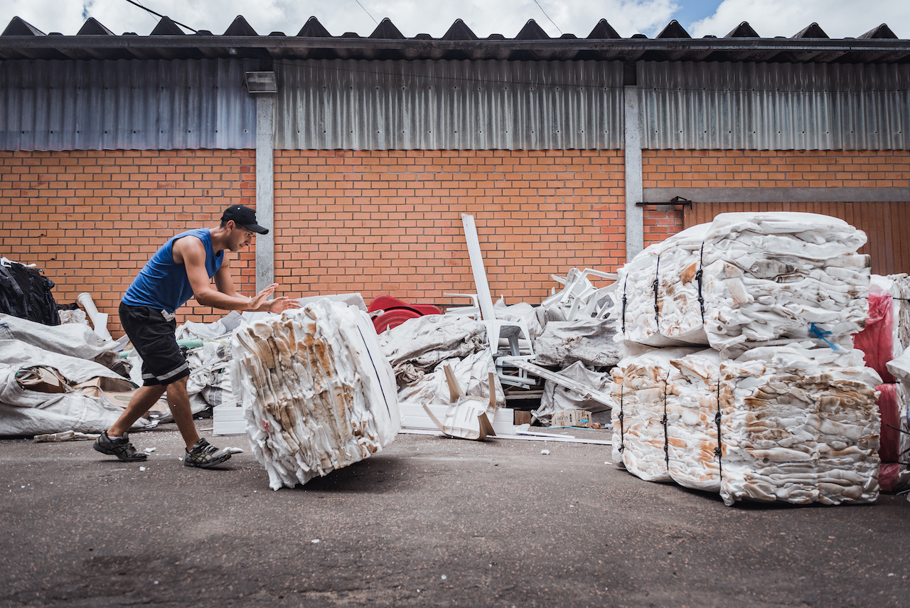 Homem empurrando pilha compactada de material reciclado